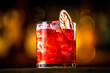 Red alcoholic cocktail in a transparent glass with dried orange decoration