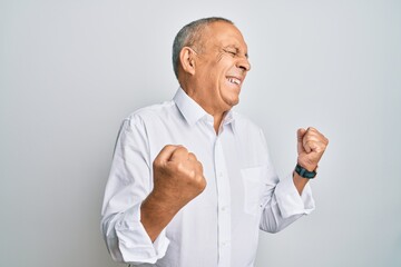 Poster - Handsome senior man wearing casual white shirt very happy and excited doing winner gesture with arms raised, smiling and screaming for success. celebration concept.