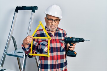 Canvas Print - Handsome mature handyman holding screwdriver wearing hardhat by construction stairs depressed and worry for distress, crying angry and afraid. sad expression.