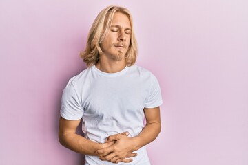 Poster - Caucasian young man with long hair wearing casual white t shirt with hand on stomach because indigestion, painful illness feeling unwell. ache concept.