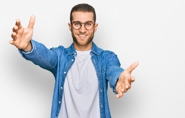 Young caucasian man wearing casual clothes looking at the camera smiling with open arms for hug. cheerful expression embracing happiness.