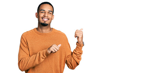 Poster - Young african american man wearing casual clothes pointing to the back behind with hand and thumbs up, smiling confident