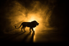 A Silhouette Of Lion Miniature Standing On Wooden Table. Creative Decoration With Colorful Backlight With Fog. Selective Focus