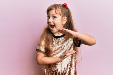 Wall Mural - Little caucasian girl kid wearing festive sequins dress gesturing with hands showing big and large size sign, measure symbol. smiling looking at the camera. measuring concept.