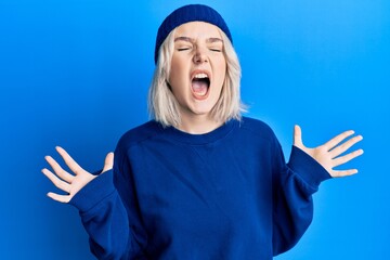 Poster - Young blonde girl wearing casual clothes crazy and mad shouting and yelling with aggressive expression and arms raised. frustration concept.