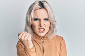 Poster - Young blonde girl wearing casual clothes angry and mad raising fist frustrated and furious while shouting with anger. rage and aggressive concept.