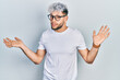 © Krakenimages.com - Young hispanic man with modern dyed hair wearing white t shirt and glasses clueless and confused expression with arms and hands raised. doubt concept.