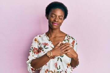 Poster - Young african american girl wearing casual clothes smiling with hands on chest with closed eyes and grateful gesture on face. health concept.