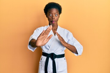 Poster - Young african american girl wearing karate kimono and black belt making fish face with mouth and squinting eyes, crazy and comical.