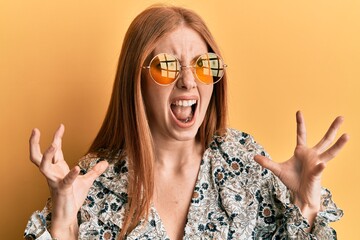 Wall Mural - Young irish woman wearing bohemian and hippie style crazy and mad shouting and yelling with aggressive expression and arms raised. frustration concept.