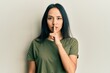 Young hispanic girl wearing casual t shirt asking to be quiet with finger on lips. silence and secret concept.