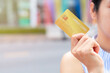 © AKGK Studio - Women hand holding gold credit card member card over blur department store background. Business, shopping, lifestyle concept. With copy space