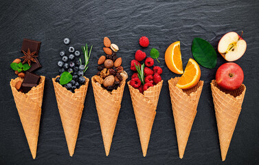 Fototapete - Various of ingredient for ice cream flavor in cones blueberry ,lime ,pistachio ,almond ,orange ,chocolate ,vanilla and coffee set up on dark stone background . Summer and Sweet menu concept.