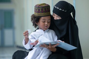 Wall Mural - Muslim mother teaches her son to read Arabic, relationship between Muslim mother and child, Mother's day