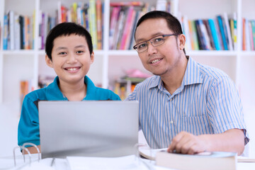 Wall Mural - Young teacher with his student using a laptop