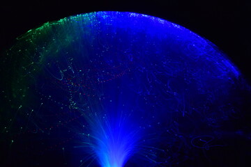 Moving light fibers creating beautiful light traces and patterns of green and blue with a black background.