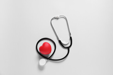 Modern stethoscope and heart on light background