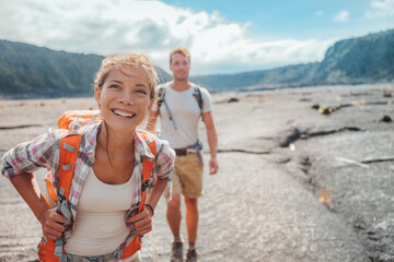 hiking couple walking with backpacks on lava field trail in hawaii. summer travel happy smiling asia