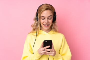 Poster - Young blonde woman wearing a sweatshirt isolated on pink background listening music and looking to mobile