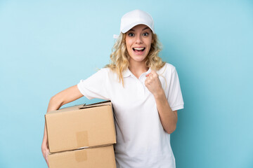 Poster - Young delivery woman isolated on blue background celebrating a victory