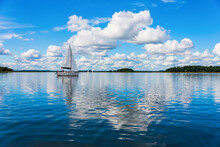 Sailing Yacht In The Lake With Gloomy Sky Before The Rain. Yacht Sailing On The Lake Against A Blue Sky With Clouds. Sailboat Vacations On A Lake.