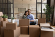 © fizkes - Portrait happy family sitting on couch with cardboard boxes, relocation and moving day concept, smiling wife and husband looking at camera, preparing to relocation, mortgage or rent concept