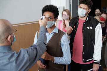 Poster - Mature bald male professor with thermometer measuring body temperature of student standing against queue of groupmates