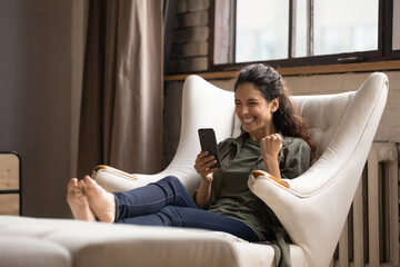 Wall Mural - Overjoyed woman looking at phone screen, received good news, unexpected money refund, job promotion or mobile game win, excited young female rejoicing success, online lottery win, showing yes gesture