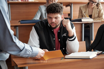 Poster - Bearded young student in casualwear looking through notes in copybook held by professor explaining him how to solve equation at lesson