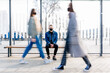 © Iryna - Lonely student man in jeans jacket wearing black facial protection mask sitting on bench of bus or tram station in a crowd of walking people. Concept for prevent for coronavirus outbreak.