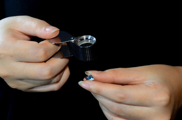 Wall Mural - woman holding a magnifying glass looking at beautiful jewelry aquamarine