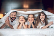 © zinkevych - Smiling family in white robes lying in bed and having fun