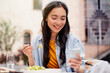 A beautiful young Asian woman is using an application to send a instant message in her smartphone device while eating a salad at the restaurant 