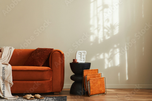 Obraz Dibond Stylish interior of living room at fancy home with design sofa, newspaper stand, pillow, blanket, sied stool, carpet decor and personal accessories in modern home decor. Template. Copy space.