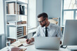 © gstockstudio - Concentrated young man in shirt and tie writing something down while sitting in the office