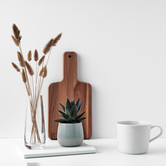 Wall Mural - A mug and potted houseplant, a stack of books, a transparent vase and a wooden board. Eco-friendly materials in interior decor, minimalism. Copy space, mock up.