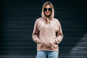 Poster - Fasion blonde woman in brown oversize hoodie, glasses and blue jeans, mockup for logo or branding design