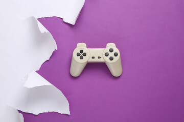 Wall Mural - Retro gamepad and torn paper sheet on purple background. Gaming concept. Top view. Copy space