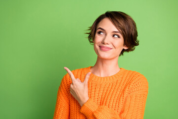 Photo of young brunette dreamy woman look empty space point finger information isolated on green color background