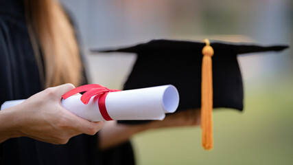 Close-up shot of a university graduate holding a degree certification to shows and celebrate education success on the college commencement day. Education stock photo