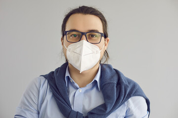 Close up headshot portrait of happy guy wearing eyeglasses and breathing through FPP2 KN95 N95 face mask to protect from air pollution or Covid 19 infection in times of global coronavirus pandemic