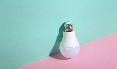 Led light bulb on blue-pink pastel background. Minimalism. Trendy shadow. Creative layout.