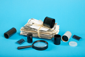 A stack of old photographs, a magnifier, a roll of film on a blue background.