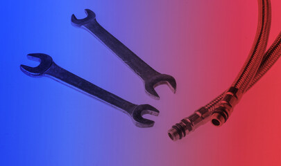 Metal plumbing hoses, wrenches isolated in red blue neon light