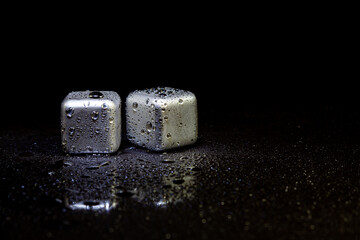 Wall Mural - Stainless steel cubes simulating ice for cooling drinks on a black surface with a reflection.