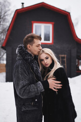 man and woman sitting on the porch of a house. young happy couple in love outdoors in the winter