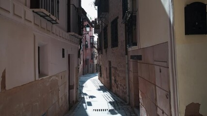 Sticker - Charming narrow street of old town of Toledo city at sunny warm day. Empty pedestrian cobblestone walkway lead along residential houses. No people. Spanish landmarks concept. Castilla-La Mancha, Spain