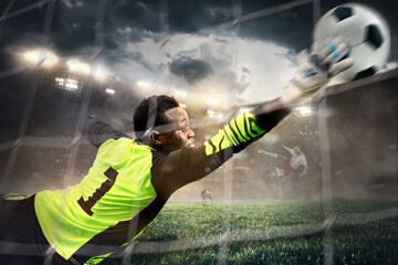 African male soccer or football player, goalkeeper in action at stadium. Young man catching ball, training, protecting goals in motion.