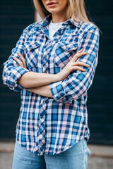 Wall Mural - Fashion portrait of beautiful woman with beautiful face, wearing grunge plaid shirt. Posing alone on wall background