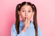 Photo portrait of small schoolgirl put finger near lips staring keeping secret isolated on pastel pink color background